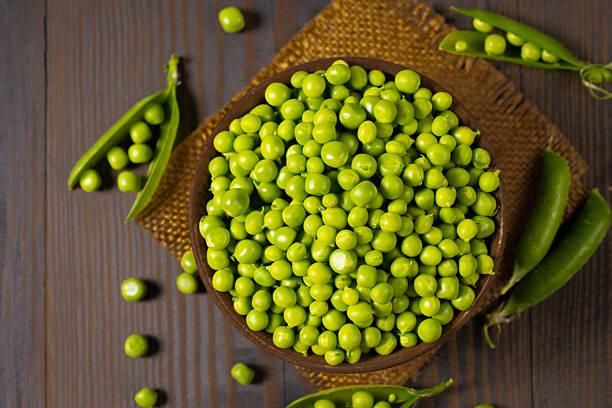 istock Fresh green peas in a bowl on a wooden table. 2223429534