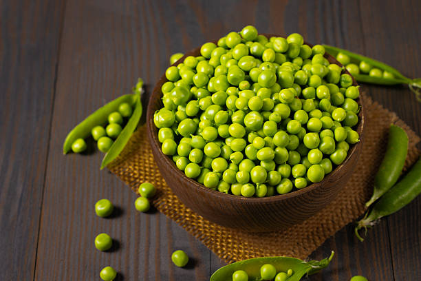 istock Fresh green peas in a bowl on a wooden table. 2223429535
