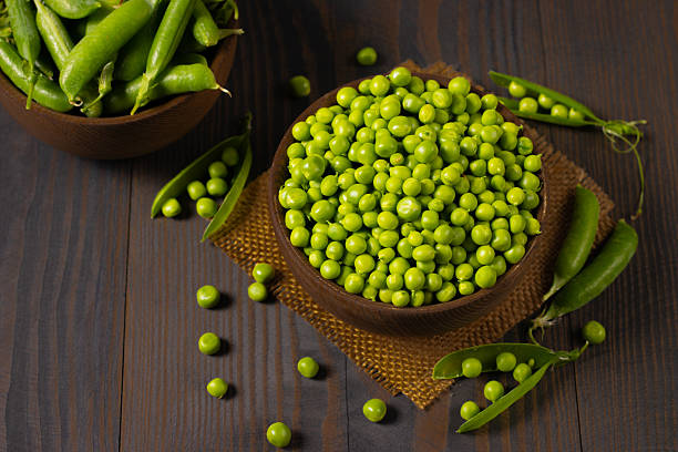 istock Fresh green peas in a bowl on a wooden table. 2223429564