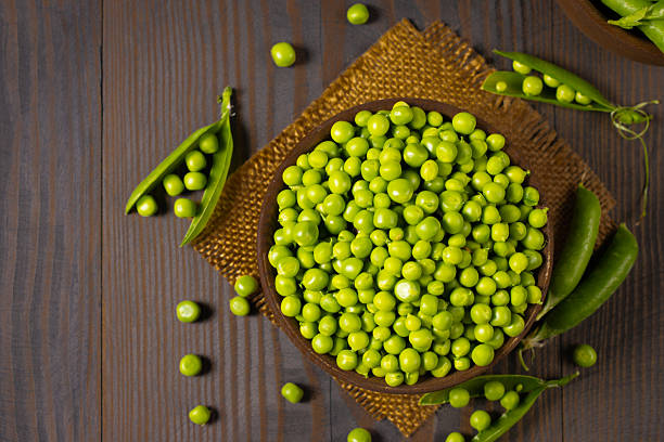 istock Fresh green peas in a bowl on a wooden table. 2223429568