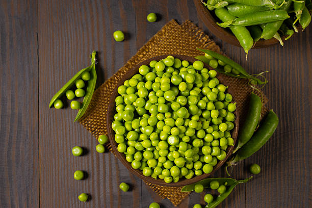 istock Fresh green peas in a bowl on a wooden table. 2223429571