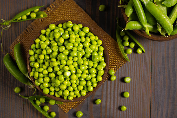 istock Fresh green peas in a bowl on a wooden table. 2223429573