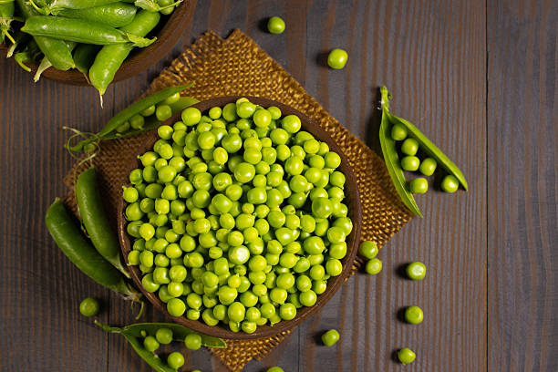 istock Fresh green peas in a bowl on a wooden table. 2223429575