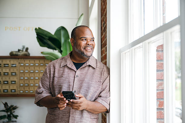 istock Office worker portrait looking through the window while holding smartphone 2223431759