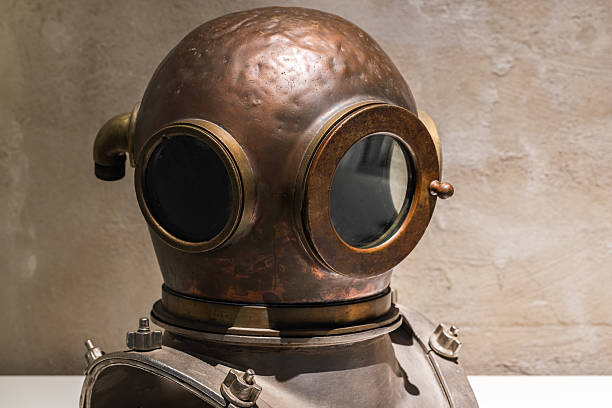 Antique diving helmet crafted from brass, displayed against a rustic textured wall, showcasing historical underwater exploration tools