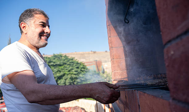 istock Smiling Man Grilling Meat Outdoors on a Sunny Day 2223432392