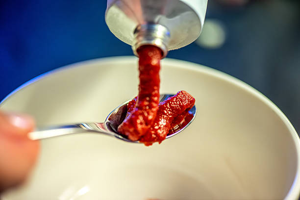 A natural kitchen moment showing a woman stirring rich tomato paste, capturing the warmth of home cooking and the textures of a delicious meal in progress.