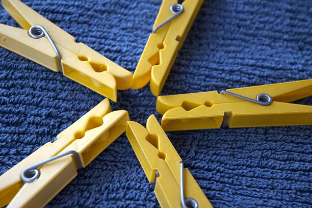 Yellow plastic clothespins on blue towel close up.