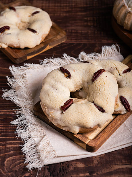 Traditional Mexican sweet bread, adorned with pecans, rest on a rustic wooden board.