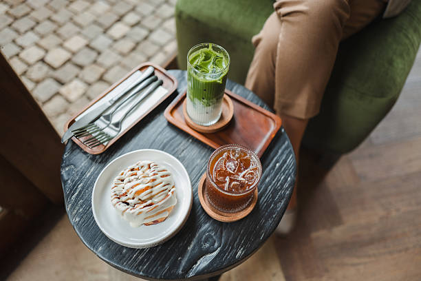 Cozy cafe table featuring a delicious pastry drizzled with icing, a vibrant matcha latte, and a refreshing iced coffee, perfect for a relaxing break