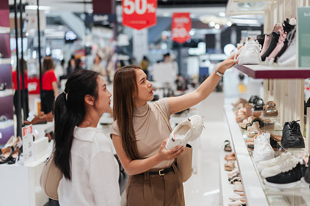 istock Two Asian women browsing white sneakers in a shoe store, pointing and discussing options. Captures shopping lifestyle, product interest, and modern female consumer behavior in retail. 2223442014