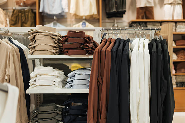 istock Neatly arranged shirts in various colors, both folded and hanging, displayed on racks inside a retail fashion store. The organized layout reflects a clean and professional shopping environment. 2223442241