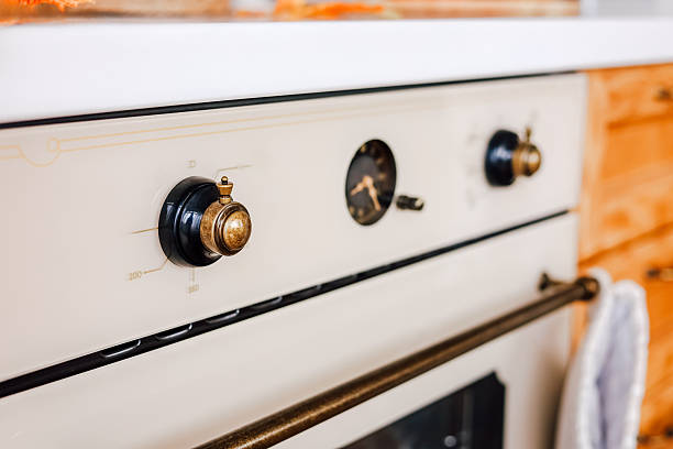 A vintage stove showcases detailed knobs and a clock adding charm to the sunny kitchen atmosphere filled with wooden cabinets.
