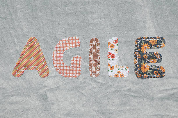 The word “AGILE” is creatively spelled out using individual letters made from various patterned fabric pieces. Each letter showcases a unique textile design, reflecting innovation, adaptability, and the colorful nature of creative workspaces or fashion-inspired concepts.
