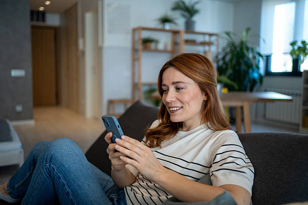 istock Smiling woman engaging with smartphone at home 2223451575