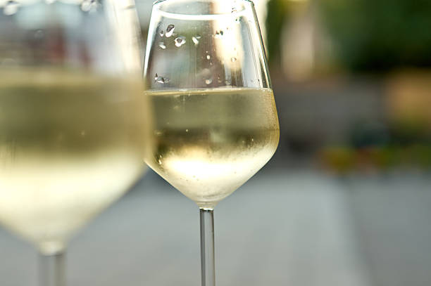 istock Two elegant wine glasses filled with refreshing cold white wine 2223457341