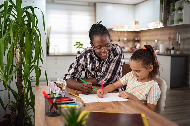 istock Young tutor helping a little girl with her homework, using colored pencils 2223461231