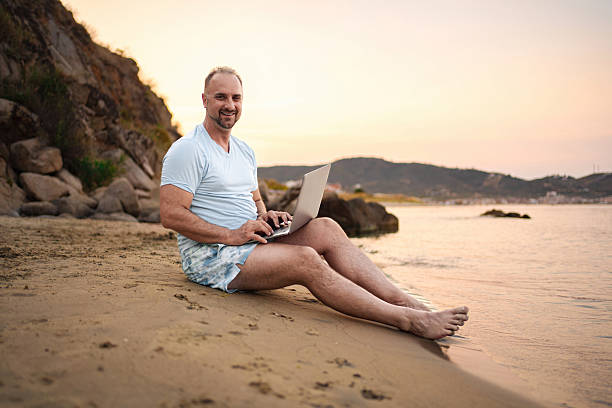 istock Freelancer working on laptop at the beach during sunset 2223461385