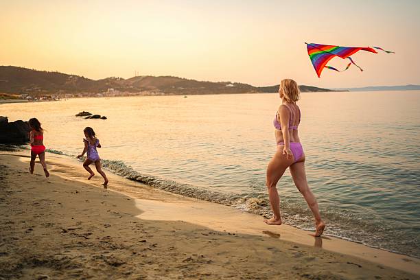 istock Mother and daughters playing with kite on the beach at sunset 2223461482