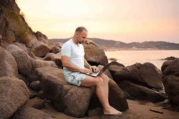 istock Digital nomad working remotely on the beach at sunset 2223461533
