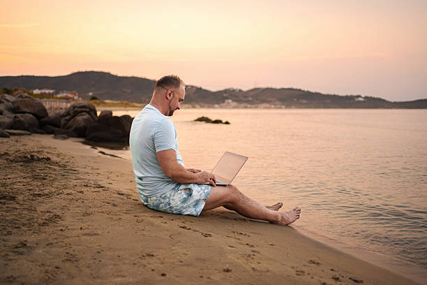 istock Freelancer working on laptop at the beach during sunset 2223461585