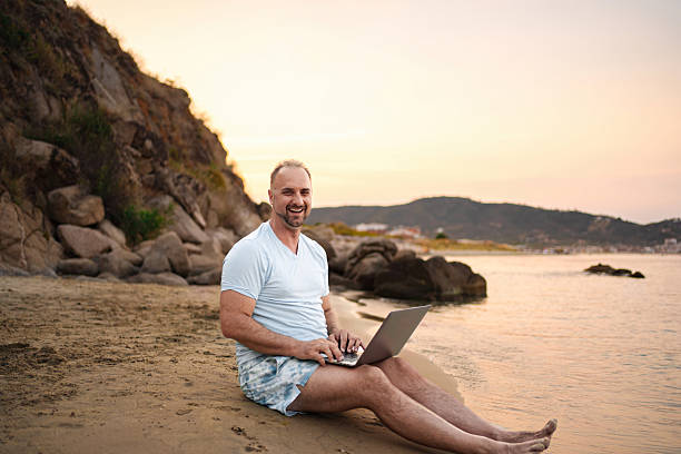 istock Freelancer working on laptop at the beach during sunset 2223461836
