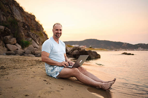 istock Mid adult man working remotely on the beach 2223461869