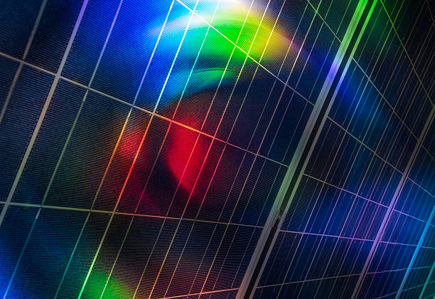 This dynamic image captures the surface of photovoltaic solar panels reflecting a spectrum of light in brilliant rainbow hues.