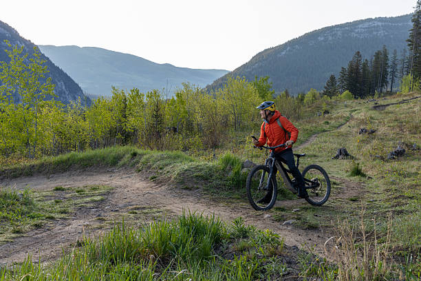 istock Mature male mountain biker uses mobile phone on trail 2223479073