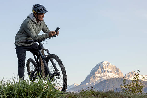 istock Mountain biker uses mobile phone in mountain meadow 2223479075