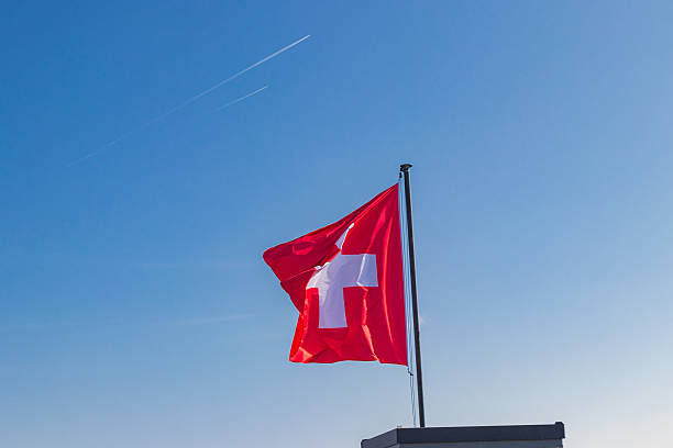 istock Red Swiss flag over the blue sky background 2223480091