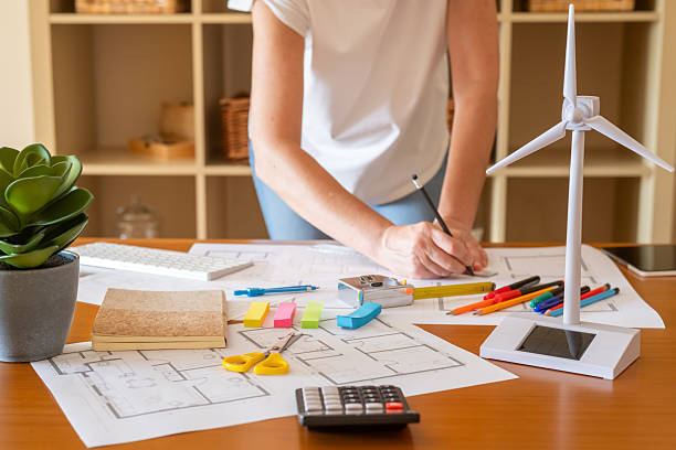 istock Female architect creating blueprints for a sustainable building project, incorporating renewable energy sources like wind and solar power to promote ecological design 2223481878