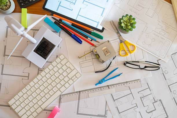 istock Desk filled with blueprints, wind turbine, solar panel, and creative tools, highlighting sustainable construction and ecological design in a modern workspace 2223482023