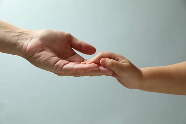 istock Mother and child holding hands on light blue background, closeup 2223482217