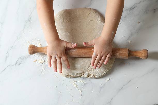 istock Little child rolling raw dough at white table, top view 2223482462