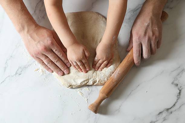 istock Father and child making dough at white table, top view 2223482530
