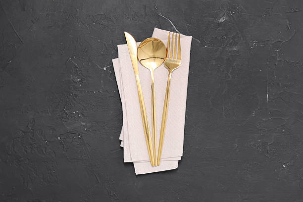 Beautiful cutlery set and kitchen towel on black table, top view
