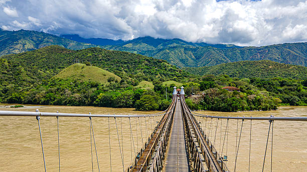Beautiful view of a suspension bridge connecting lush hills with a river in Santa Fe de Antioquia, Colombia.
