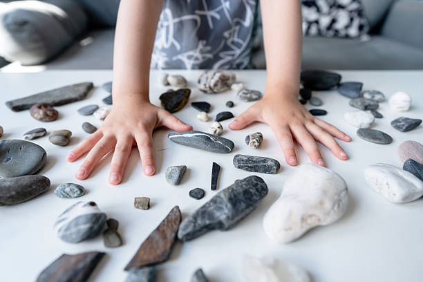 istock Child's Hands And Assorted Rocks on a White Table in a Casual Setting 2223486044