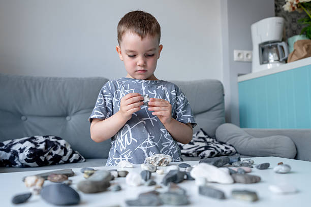 Curious young child examining stones on a table, fostering creativity and tactile learning in a bright and cozy indoor environment.