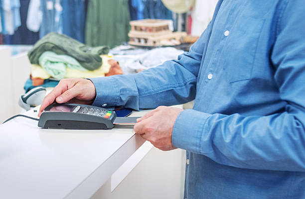 istock Payment processing at checkout counter. Mature male buyer completes purchase using card reader terminal. 2223488550