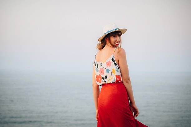 Happy young woman by the sea. Smiling young woman with a hat.
