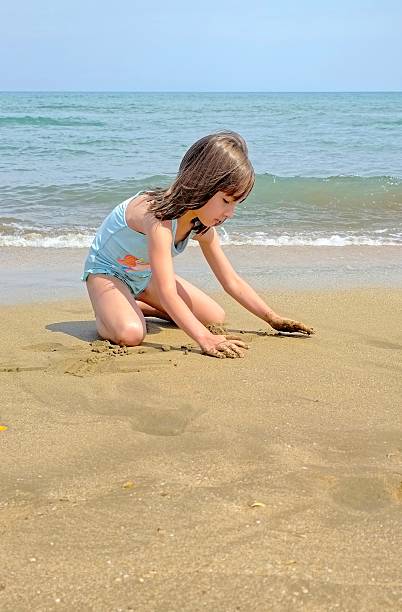 istock little girl is playing with sand on the beach 2223493644