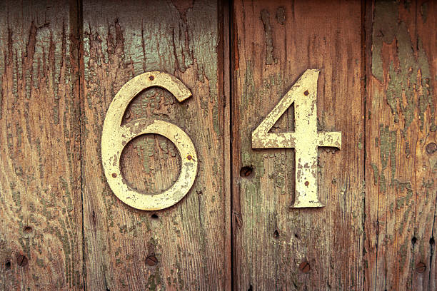 istock Weathered house number 64 on an old wooden surface 2223494390