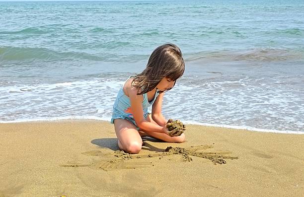 little girl is playing with sand on the beach. High quality photo