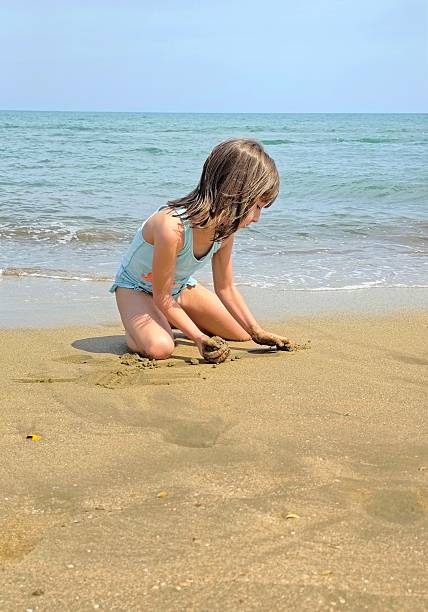 istock little girl is playing with sand on the beach 2223494587