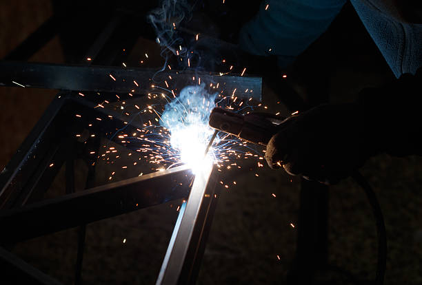 A blacksmith is working on a piece of metal, using a welding torch to melt and shape it. Concept of craftsmanship and skill, as well as the physical labor involved in the process
