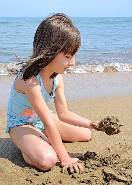 istock little girl is playing with sand on the beach 2223494673
