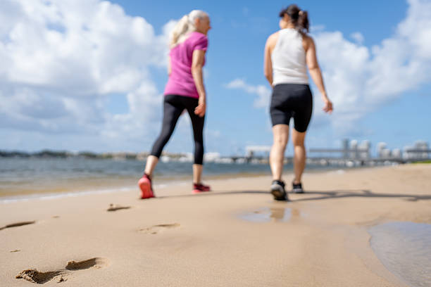 Two friends walk along the sandy shoreline on a sunny day