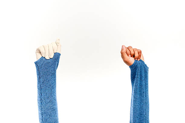 Two hands raised up one human and one prosthetic both wearing blue knit sleeves on a white background